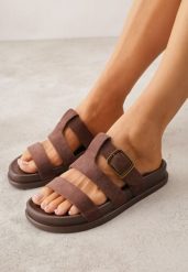 Brązowe Klapki Ozdobione Geometrycznymi Paskami i Metaliczną Klamrą Hossei. Brązowe klapki Renee, bez wzorów, casualowe, bez obcasa, na płaskiej podeszwie, bez zapięcia. Za 79.99 zł.