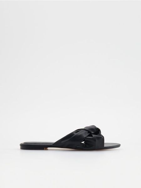 Klapki z imitacji skóry - czarny. Czarne klapki Reserved, bez wzorów, ze skóry, klasyczne, bez obcasa, bez zapięcia. W wyprzedaży za 39.99 zł.