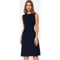 Sukienka elegancka trapezowa bez rękawów z paskiem i guzikami granat. Sukienki Nife, do pracy, bez wzorów, biznesowe, bez kołnierzyka, bez ramiączek, trapezowe. W wyprzedaży za 224.00 zł.