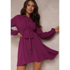 Fioletowa Sukienka Rozkloszowana z Gumką w Pasie Thelo. Fioletowe sukienki Renee, m, bez wzorów, z tkaniny, eleganckie, bez kołnierzyka, bez ramiączek, mini, kopertowe. W wyprzedaży za 63.99 zł.