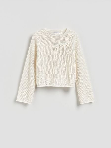 Sweter z ozdobną aplikacją - kremowy. Białe swetry Reserved, l, z aplikacjami, z bawełny, bez ramiączek. Za 119.99 zł.