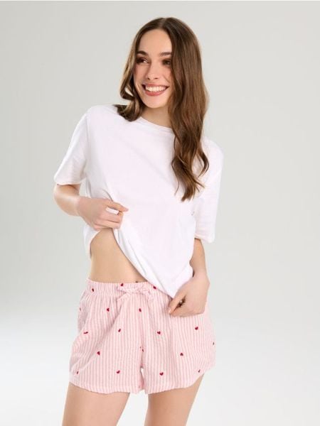 Bawełniana dwuczęściowa piżama w paski z nadrukiem w serca - kremowy. Białe piżamy Sinsay, l, bez wzorów, z bawełny, bez kołnierzyka, bez ramiączek. Za 39.99 zł.