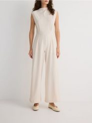 Kombinezon z długimi nogawkami - złamana biel. Kombinezony Reserved, l, bez wzorów, z dzianiny, bez kołnierzyka, bez ramiączek, długie. Za 129.99 zł.
