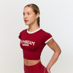 Koszulka damska fitness slim czerwona Varsity. Czerwone t-shirty sportowe GYMBEAM, l, bez wzorów, z materiału, bez ramiączek, na fitness i siłownię. Za 88.90 zł.