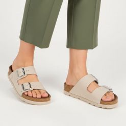 Klapki Damskie Rieker, cholewka skóra naturalna gładka dwa szerokie paski z metalowymi klamrami odkryte palce regulowane zapięcie. Szare klapki Rieker, bez wzorów, ze skóry, bez obcasa, bez zapięcia. Za 299.00 zł.