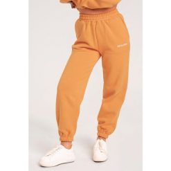 Spodnie fitness damskie Gym Glamour dresowe. Brązowe spodnie dresowe GYM GLAMOUR, bez wzorów, z dresówki, na fitness i siłownię. Za 189.99 zł.