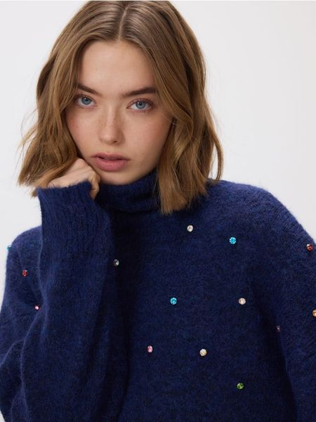 Sweter z błyszczącą aplikacją - granatowy. Niebieskie swetry Reserved, l, z aplikacjami, z dzianiny, bez ramiączek. Za 129.99 zł.