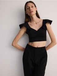 Bluzka z falbankami - czarny. Czarne bluzki Reserved, l, bez wzorów, z dzianiny, bez kołnierzyka, bez ramiączek. W wyprzedaży za 35.99 zł.