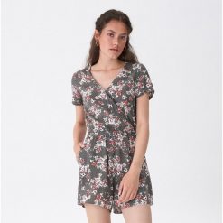 Kombinezon w kwiaty - Khaki. Brązowe kombinezony House, l, bez wzorów, bez kołnierzyka, bez ramiączek. W wyprzedaży za 39.99 zł.