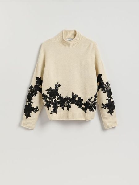 Sweter z ozdobną aplikacją - kremowy. Białe swetry Reserved, l, z aplikacjami, z dzianiny, bez ramiączek. Za 159.99 zł.