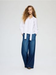 Bawełniana bluzka z wiązaniem - biały. Białe bluzki Reserved, l, bez wzorów, z bawełny, bez kołnierzyka, bez ramiączek. Za 139.99 zł.