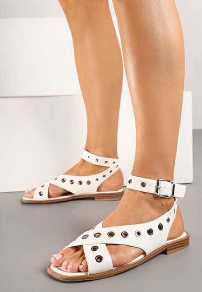 Białe Sandały Typu Gladiatorki z Kwadratowym Noskiem Zdobione Nitami Annivelle. Białe sandały Renee, z aplikacjami, z jeansu, bez obcasa, na płaskiej podeszwie, bez zapięcia. Za 69.99 zł.