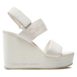 Sandały Calvin Klein Jeans. Białe sandały Calvin Klein Jeans, bez wzorów, z jeansu, bez obcasa, na koturnie, bez zapięcia. Za 369.99 zł.