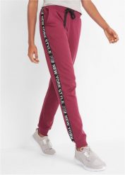 Spodnie dresowe ze ściągaczem i napisem. Czerwone spodnie dresowe bonprix, bez wzorów, z dresówki. Za 129.99 zł.