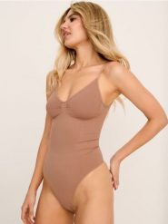 Modelujące body na ramiączkach - kremowy. Białe body i gorsety Sinsay, bez wzorów, bez ramiączek. Za 39.99 zł.